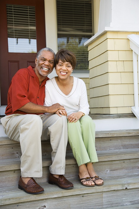Image of an older couple sitting on the steps in front of a house